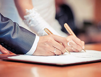 結婚誓約書にサインをするカップルの手